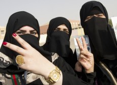 Kuwaiti girls give a victory sign as they stand in front of a polling station in Jahra