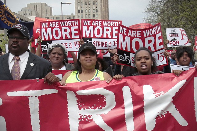 A group of workers and labor activists march down West Grand Boulevard as they demand a raise in the minimum wage for fast food workers in Detroit