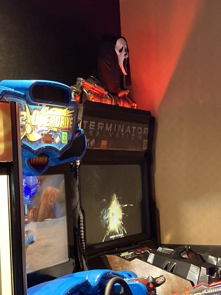 a ghostface mask on top of a terminator video arcade machine 
