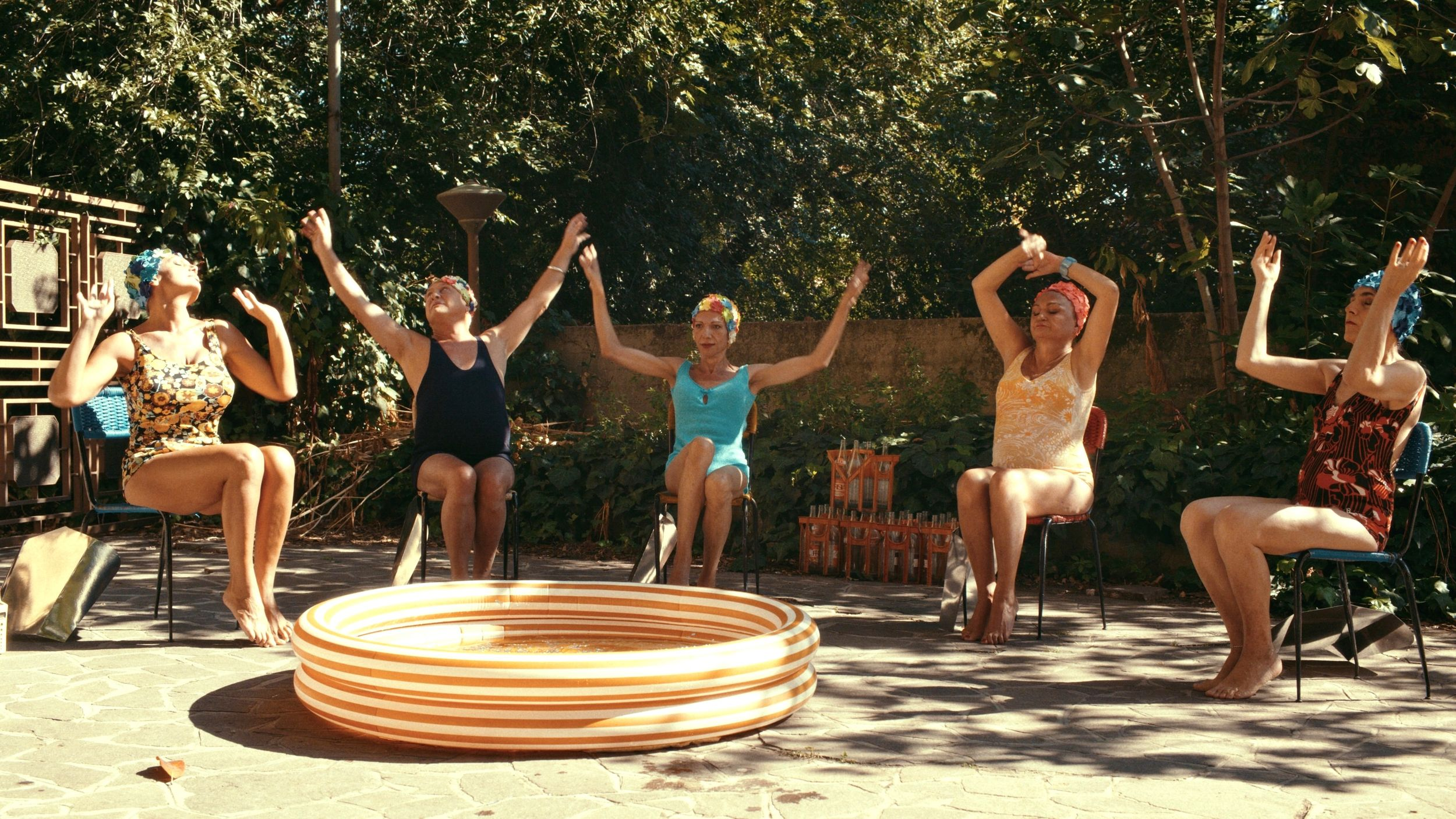 Trans women sit joyfully around an outdoor kiddie pool