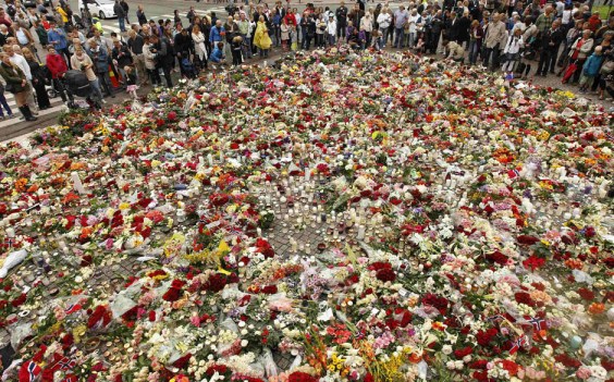 People pay their respects at a sea of floral tributes to the victims of Friday's attacks, outside the cathedral of Oslo