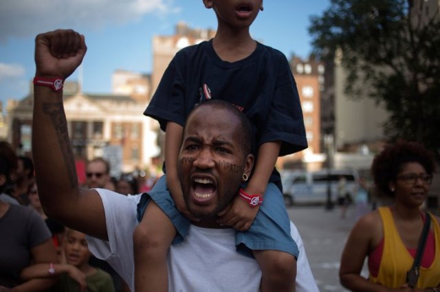 "Terill Powell carries his five-year-old son Maurice Powell amidst hundreds of activists who are demanding justice for Trayvon Martin while marching to Times Square from New York's Union Square July 14, 2013.  U.S. President Barack Obama called for calm on Sunday after the acquittal of George Zimmerman in the shooting death of unarmed black teenager Trayvon Martin, as thousands of civil rights demonstrators turned out at rallies to condemn racial profiling. Zimmerman, cleared late on Saturday by a Florida jury of six women, still faces public outrage, a possible civil suit and demands for a federal investigation." (REUTERS/Adrees Latif)