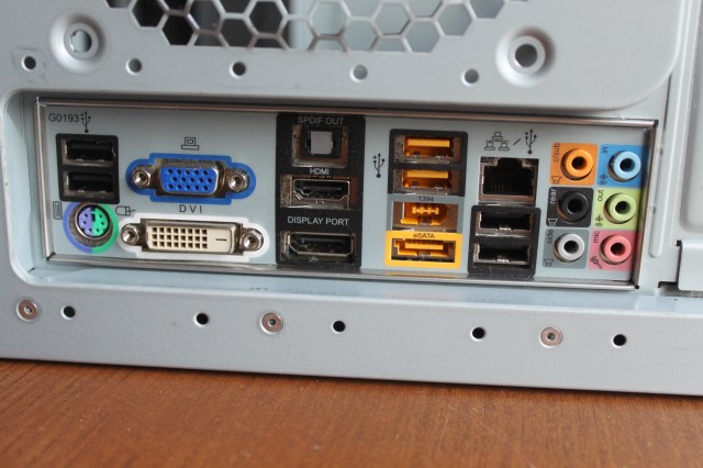 Hold the motherboard so the ports poke out through the holes.
