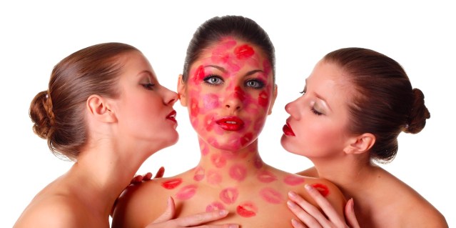 woman covered in lipstick with two women kissing her