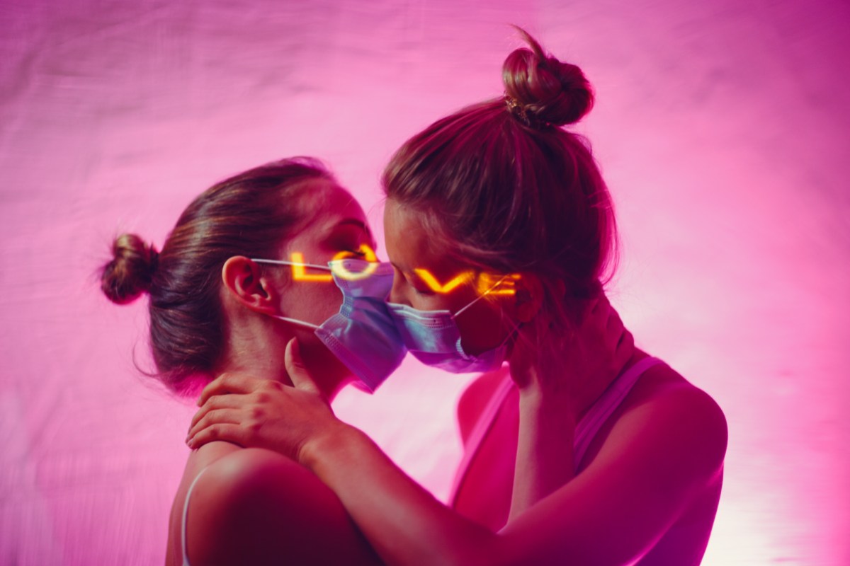 Portrait of two kissing lesbian women in medical face masks