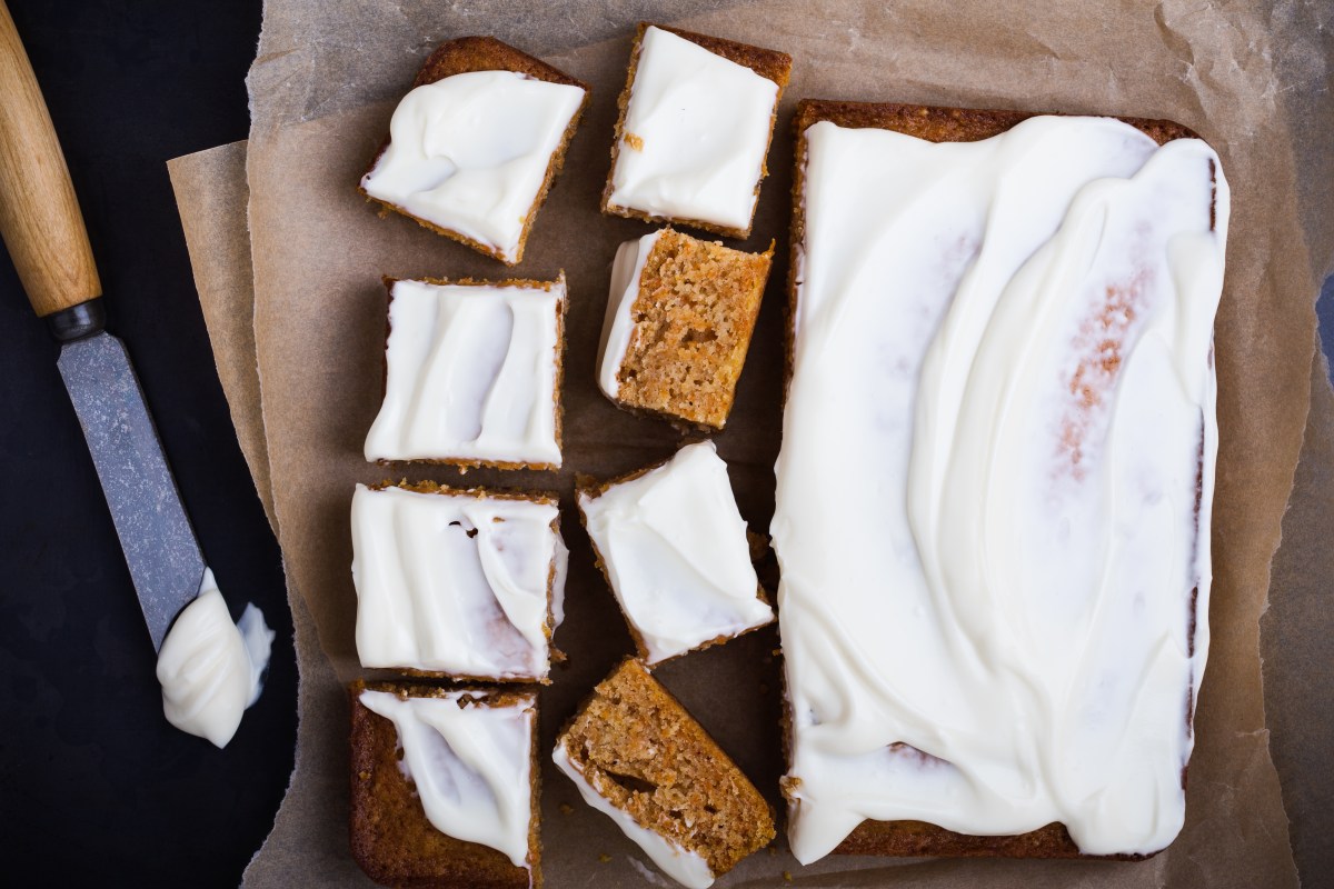 Homemade pumpkin sheet cake with cream cheese frosting sliced into squares, top view