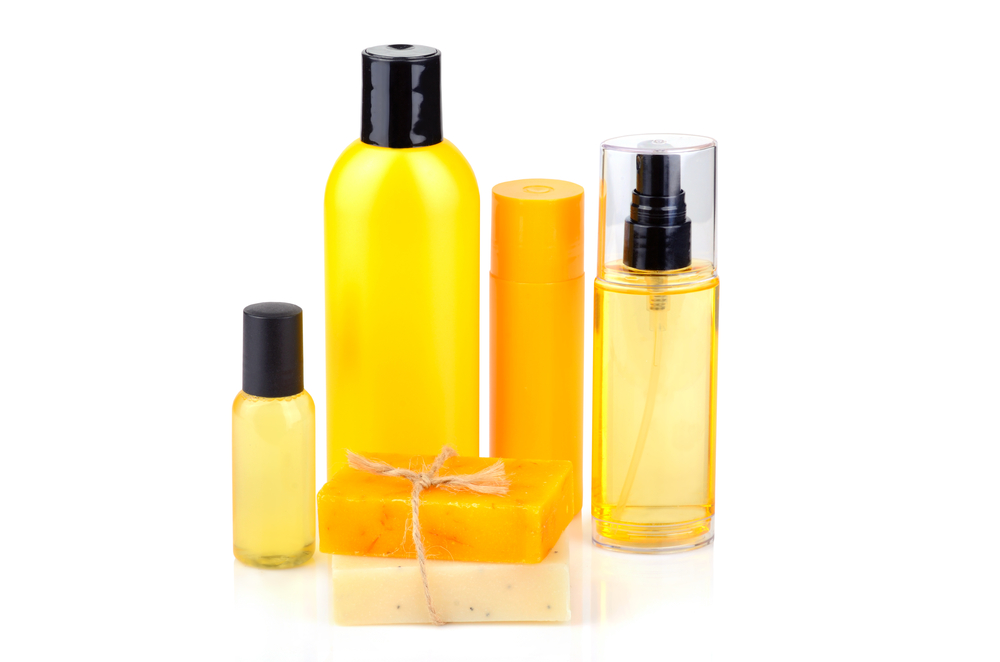 Several golden-colored bottles and bars of soap sit in a brightly lit field of white. These represent the most basic steps of a skincare routine.