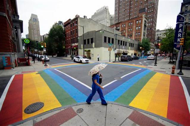 A woman walks past a rainbow crosswalk in support of the LGBT community at the intersection of 13th and Locust streets, Thursday, June 25, 2015, in Philadelphia. (AP Photo/Matt Slocum)