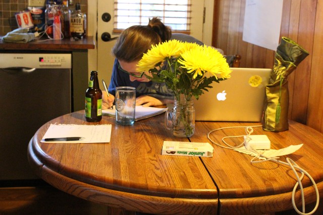 Heather is in her natural habitat, behind a vase of zinnias