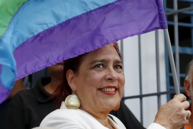 Tamara Adrian holds a LGBT flag as she arrives to register her candidacy for the upcoming parliamentary elections at an office of the National Electoral Council (CNE) in Caracas August 7, 2015. REUTERS/Carlos Garcia Rawlins