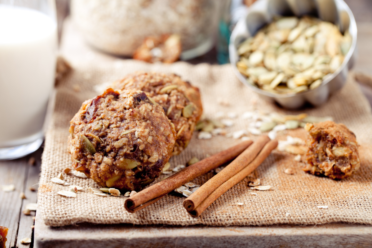 Oatmeal pumpkin cookies on a wooden slab next to cinnamon sticks