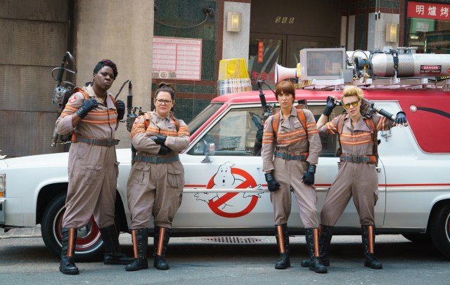 The ladies of Ghostbusters in front of their Ghostbusters car