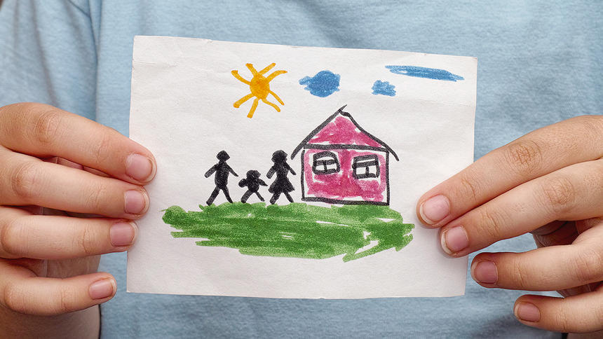 Child holds a drawn house with family