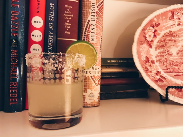 photo of completed cocktail in front of my mother's book collection and decorative plate