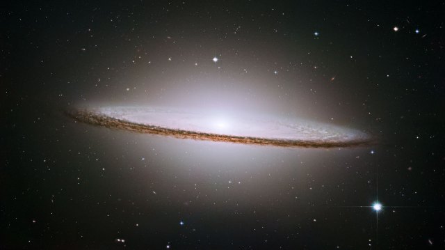 NASA/ESA Hubble Space Telescope has trained its razor-sharp eye on one of the universe's most stately and photogenic galaxies, the Sombrero galaxy, Messier 104 (M104). The galaxy's hallmark is a brilliant white, bulbous core encircled by the thick dust lanes comprising the spiral structure of the galaxy. As seen from Earth, the galaxy is tilted nearly edge-on. We view it from just six degrees north of its equatorial plane. This brilliant galaxy was named the Sombrero because of its resemblance to the broad rim and high-topped Mexican hat. At a relatively bright magnitude of +8, M104 is just beyond the limit of naked-eye visibility and is easily seen through small telescopes. The Sombrero lies at the southern edge of the rich Virgo cluster of galaxies and is one of the most massive objects in that group, equivalent to 800 billion suns. The galaxy is 50,000 light-years across and is located 30 million light-years from Earth.