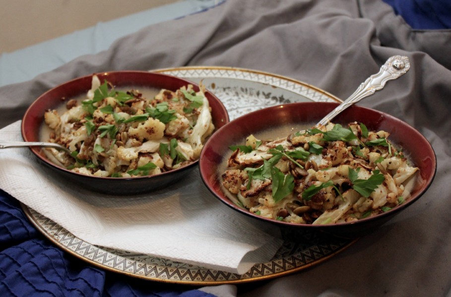 Two plates of cauliflower on a tray on a bed.