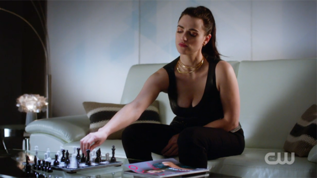 Lena reaches for a chess piece 
