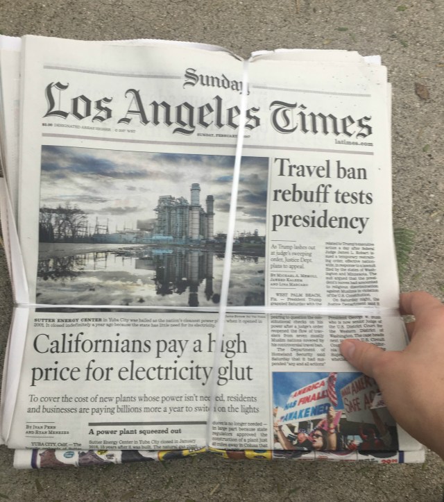 The front page of a Sunday edition of the Los Angeles Times, still wrapped in its packaging after being dropped off in the driveway.