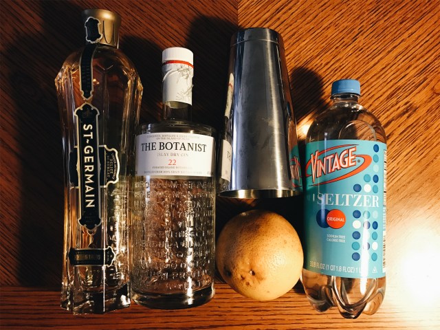 photo of ingredients: gin, seltzer, saint germain, a grapefruit and a Boston shaker