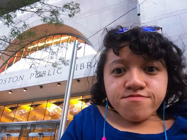 Sandy, a young Asian-American woman, poses for a selfie in front of the Boston Public Library