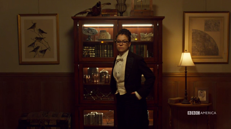 Cosima is standing in her tux with her hands in her pockets