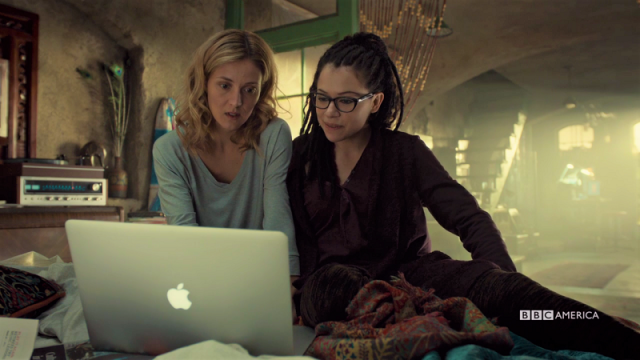 Cosima and Delphine sit together on the bed on their skype date just all casual and happy