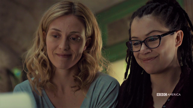 Delphine and Cosima smile at their computer with genuine happiness