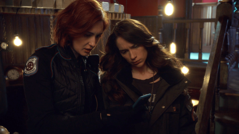 Haught and Wynonna look at NIcole's phone