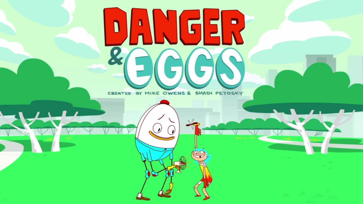 Image: Danger and Eggs promotional photograph. Neon green ground with two darker green trees near the back. Behind the park is a skyline. In the foreground, an egg wearing jeans with two legs is blowing a fan on a small human-like creature with a missing tooth. Words read "Danger and Eggs."