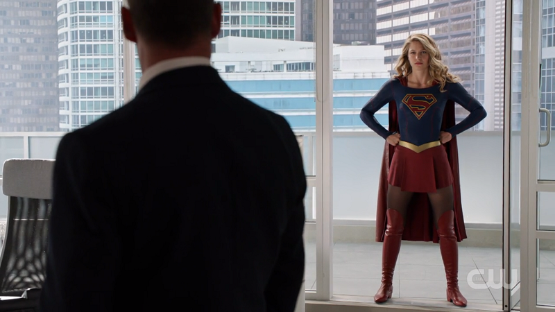 Supergirl does her stance in the balcony doorway