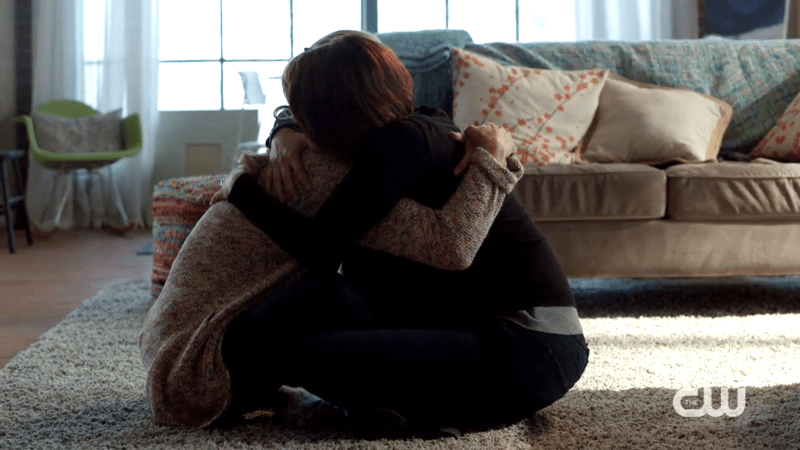 Alex and Kara hug while sitting