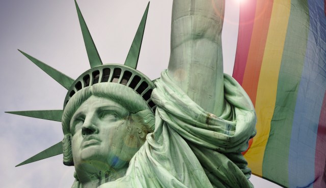 statue of liberty in front of a rainbow flag
