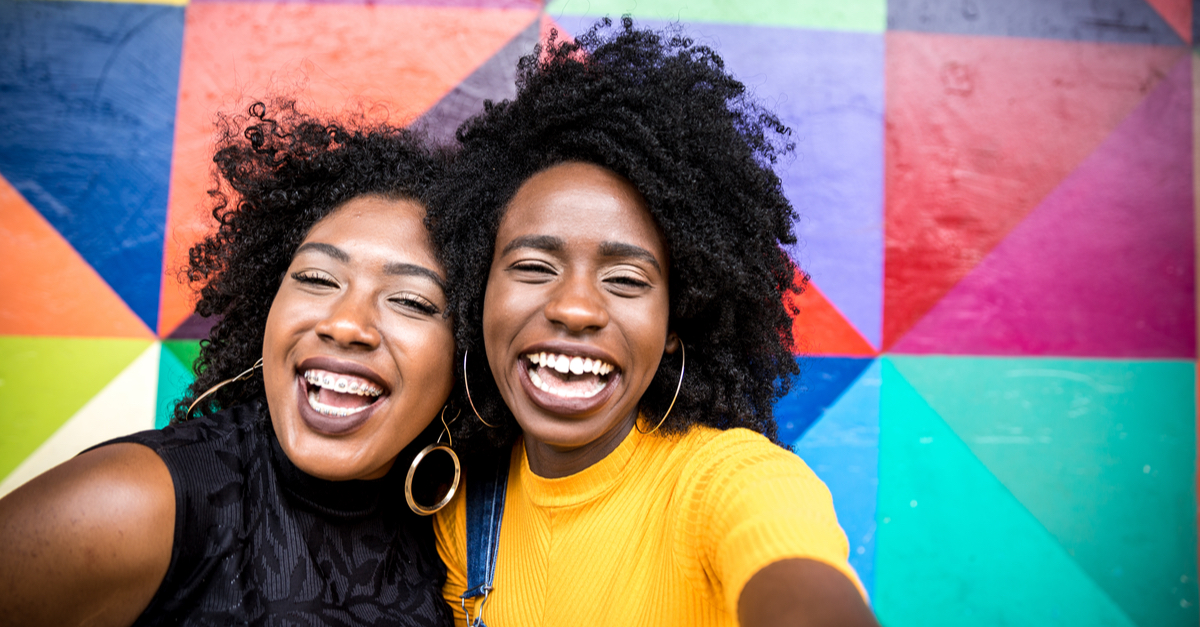 Black women smiling over a rainbow collage background