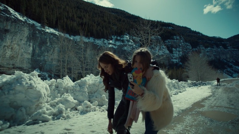 Waverly holds the mitti n her mouth while trying to get service on her flip phone and holding up her sister