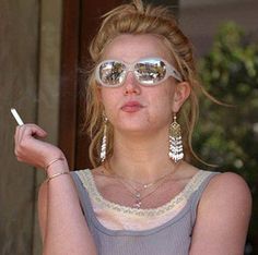 Britney Spears smokes a cigarette and stares into the middle distance, lips pursed.