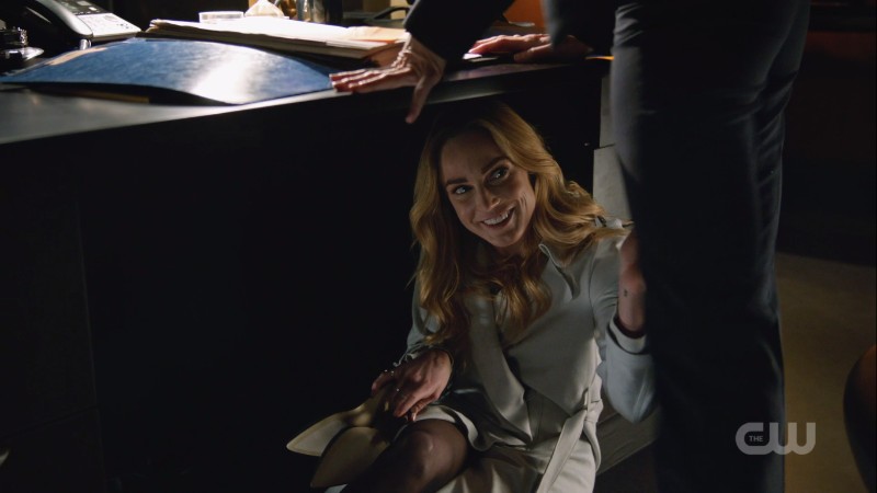 Sara is under Ava's desk and smirking