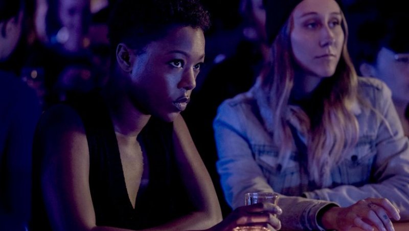 Image: Moira (Samira Wiley) is sitting at a darkened bar, looking intense. 