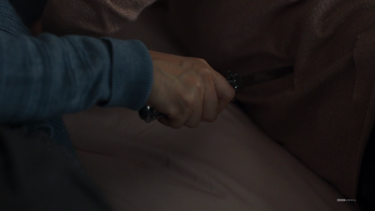 A close up of Eve's hand holding a knife against a leg in Killing Eve