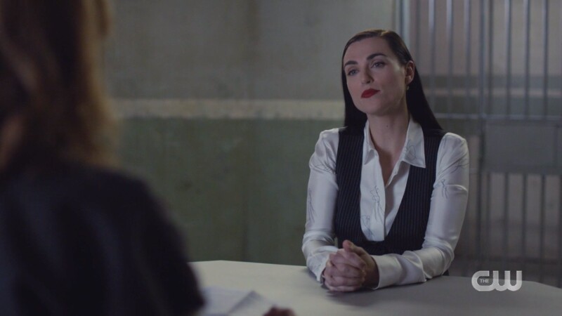 Lena is in a white silky blouse and a black pinstripe vest and her hair is down but kind of slicked back