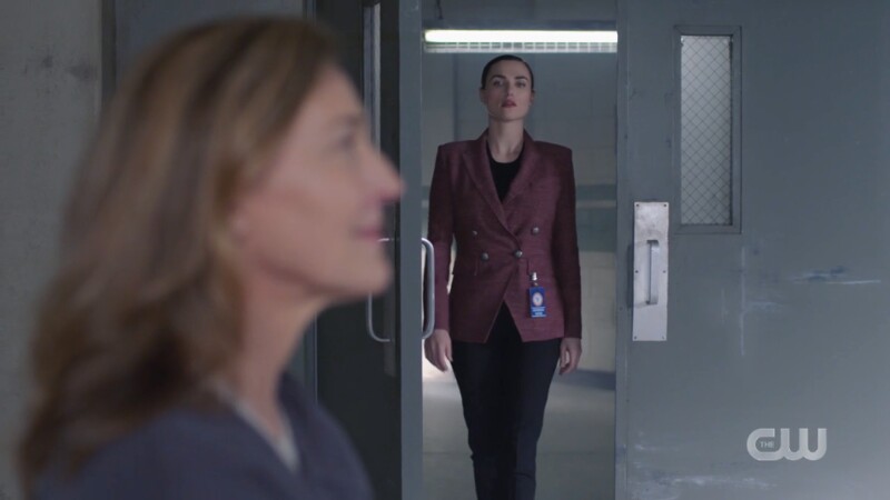 Lena struts into the room wearing a tweed-ish but cute purple blazer and black pants 