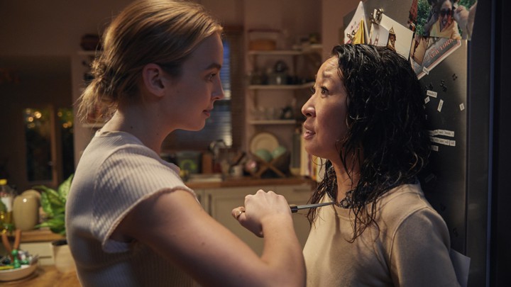 Villanelle (Jodie Comer) holds Eve (Sandra Oh) at knifepoint against a refrigerator