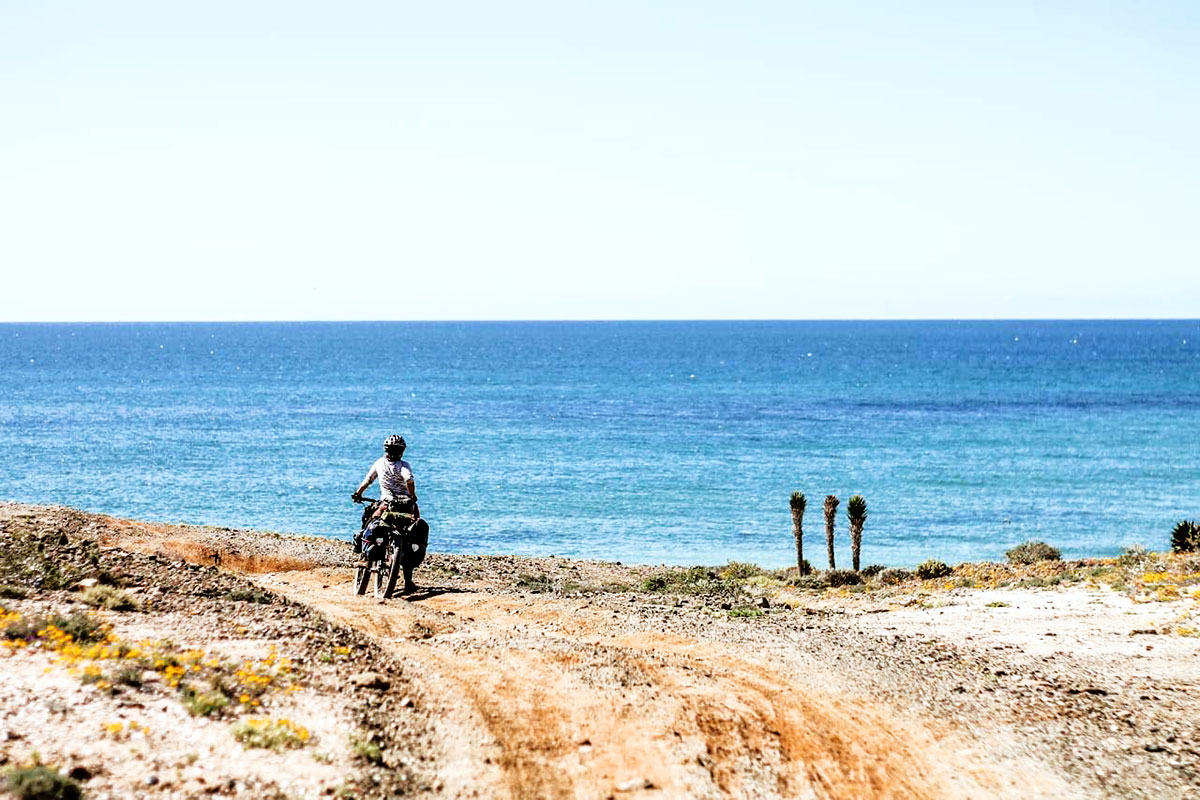 author on bike in front of ocean