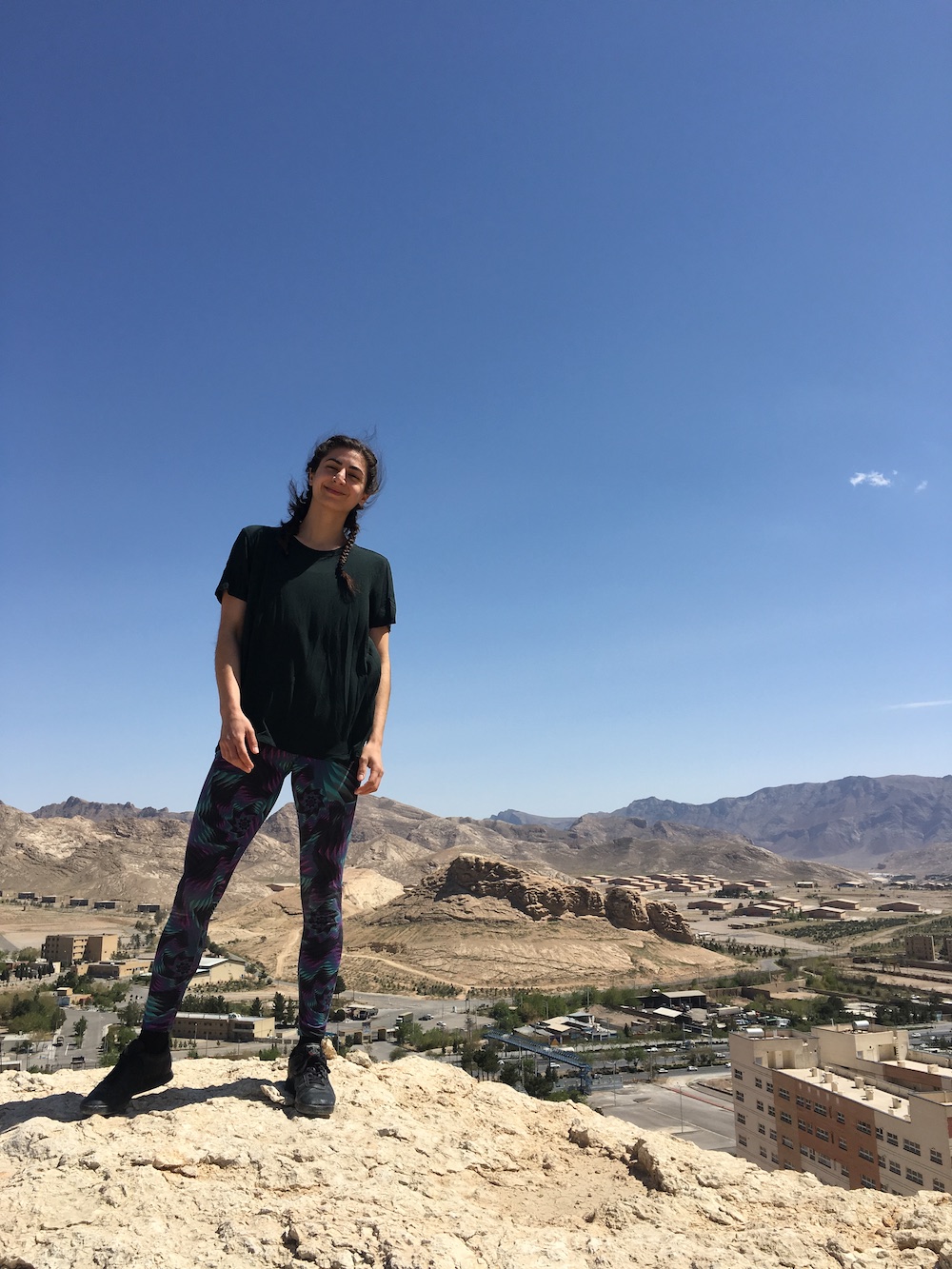 Portrait of the author standing on a rock outcropping with a city behind her