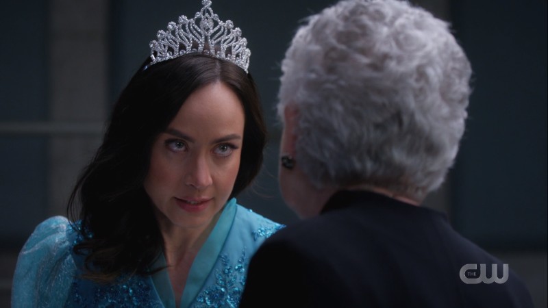 Nora is wearing a tiara and a puffy blue dress but also she's glowering
