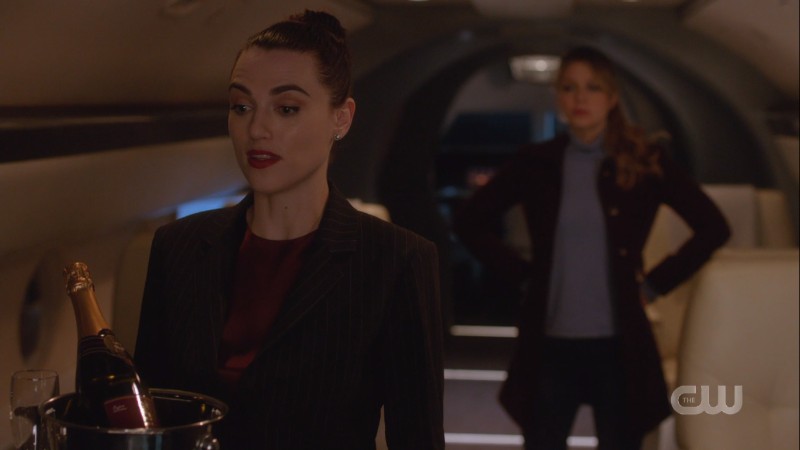 Lena talks while Kara has her glasses off and is in supergirl stance behind her