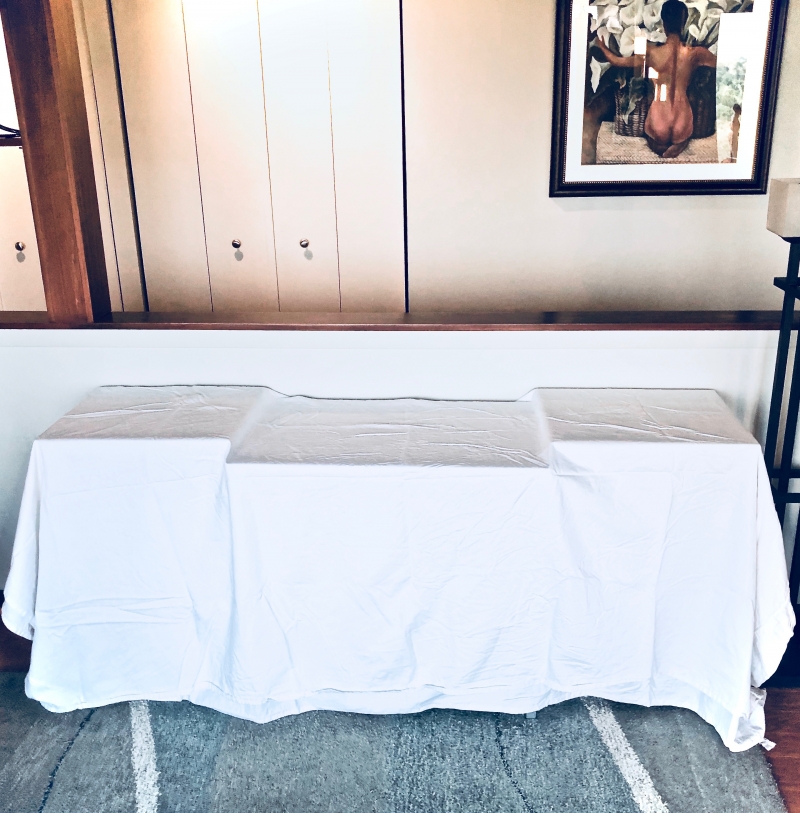 A living room table covered in a plain white tablecloth.