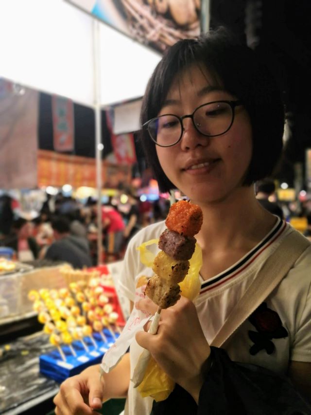 Author at night market, smiling at delicious food.