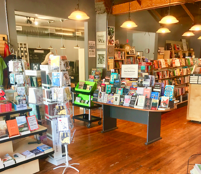 A photo of the interior of a bookstore, with several shelves and display tables visible