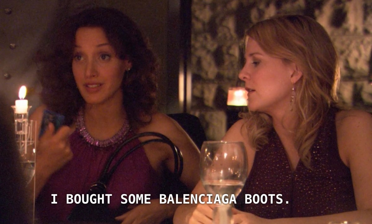 Bette (wearing a purple cocktail dress) sits to the left of Tina (also wearing a purple cocktail dress, but darker than Bette's). Bette says, "I bought some Balenciaga boots"