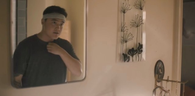 Leo looks in the bathroom mirror in a t-shirt with a sweatband 